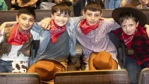 Four school children in cowboy outfits in the audience at the Big Sing