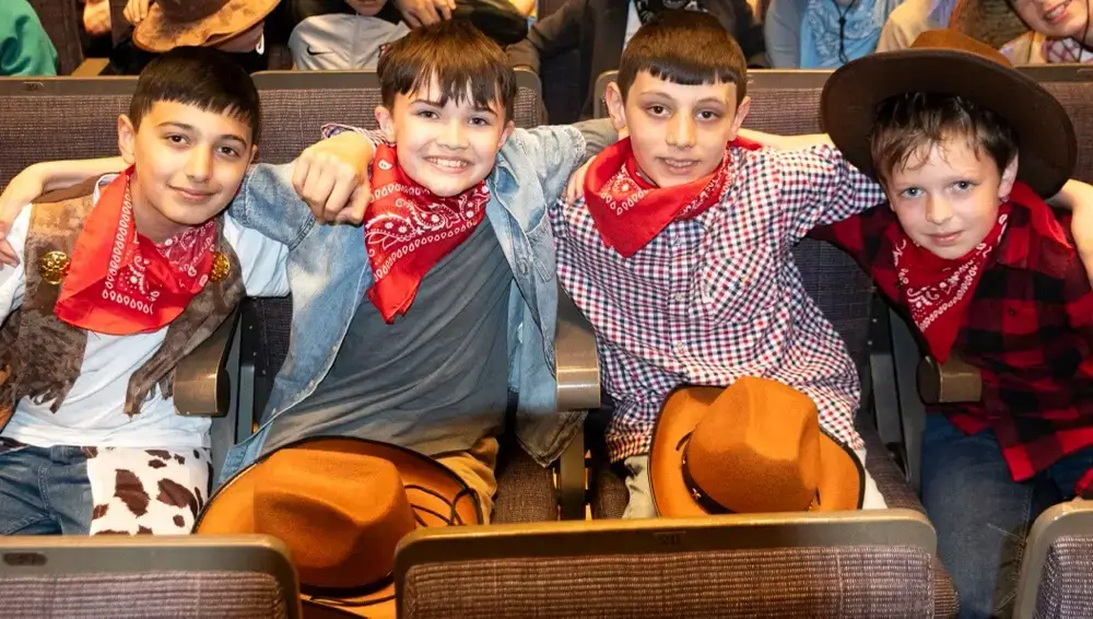 Four school children in cowboy outfits in the audience at the Big Sing