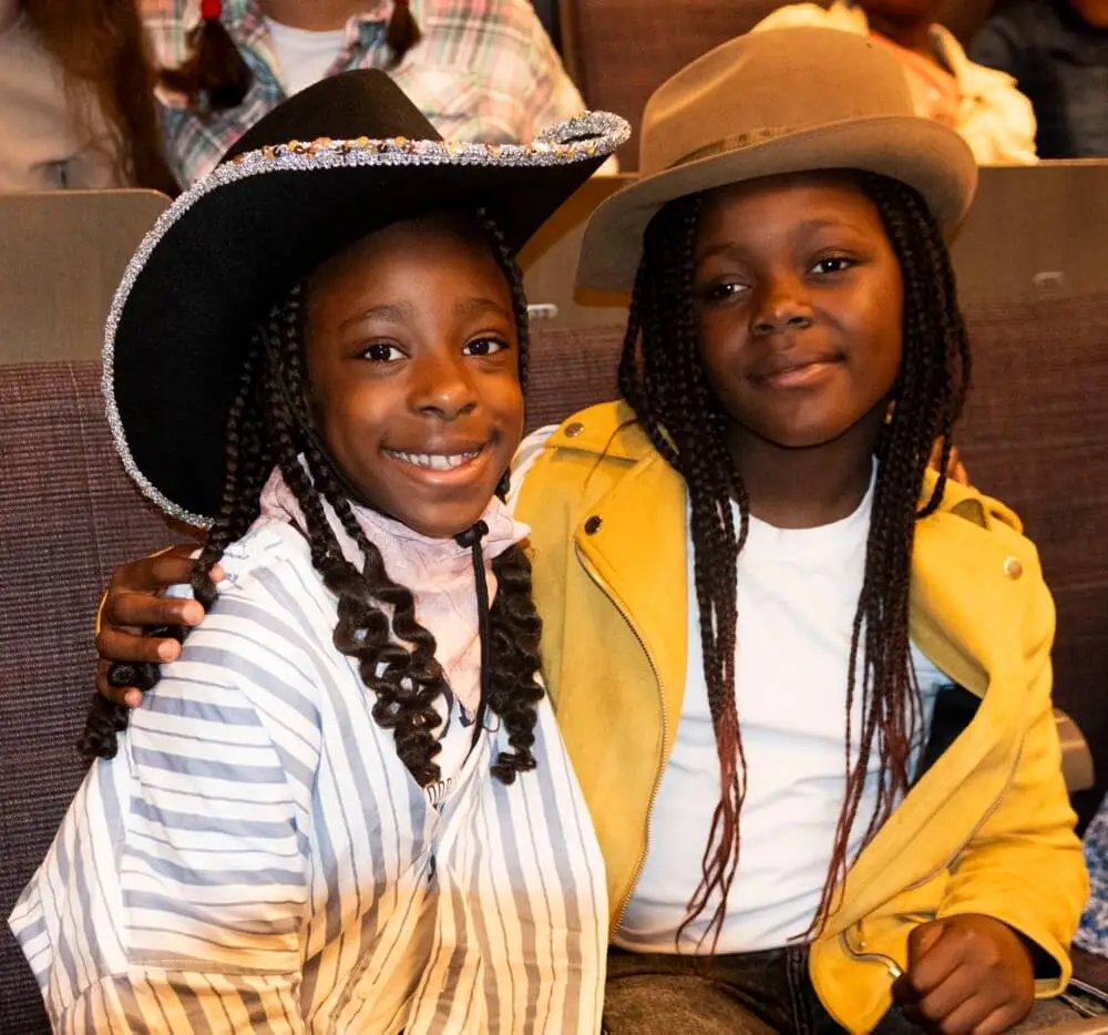Two school children dressed in cowboy hats sitting in the audience for the Big 'Country' Sing.