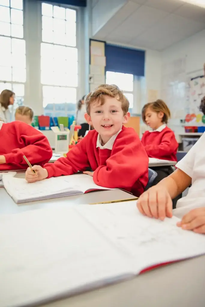 pupil holding pen smiles at camera