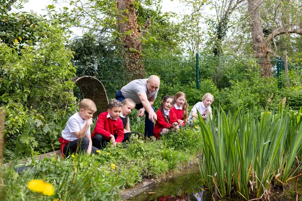 a teacher with pupils outside on a field visit