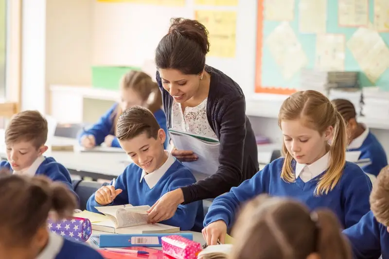 teacher helping pupils at a desk 1