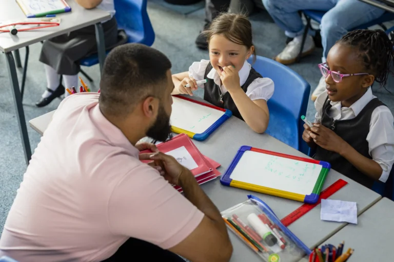 teacher speaking to two pupils at desk
