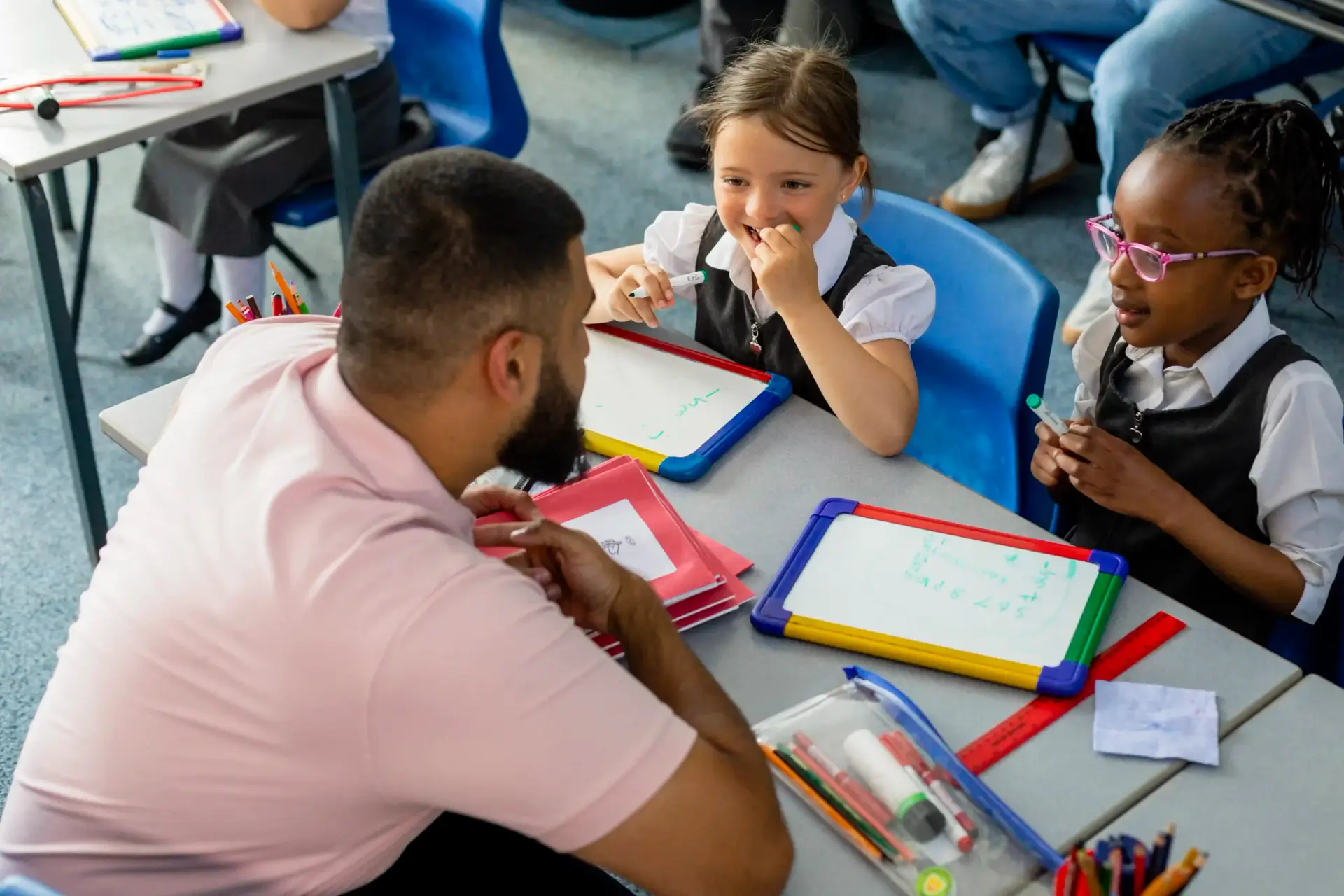 teacher speaking to two pupils at desk scaled